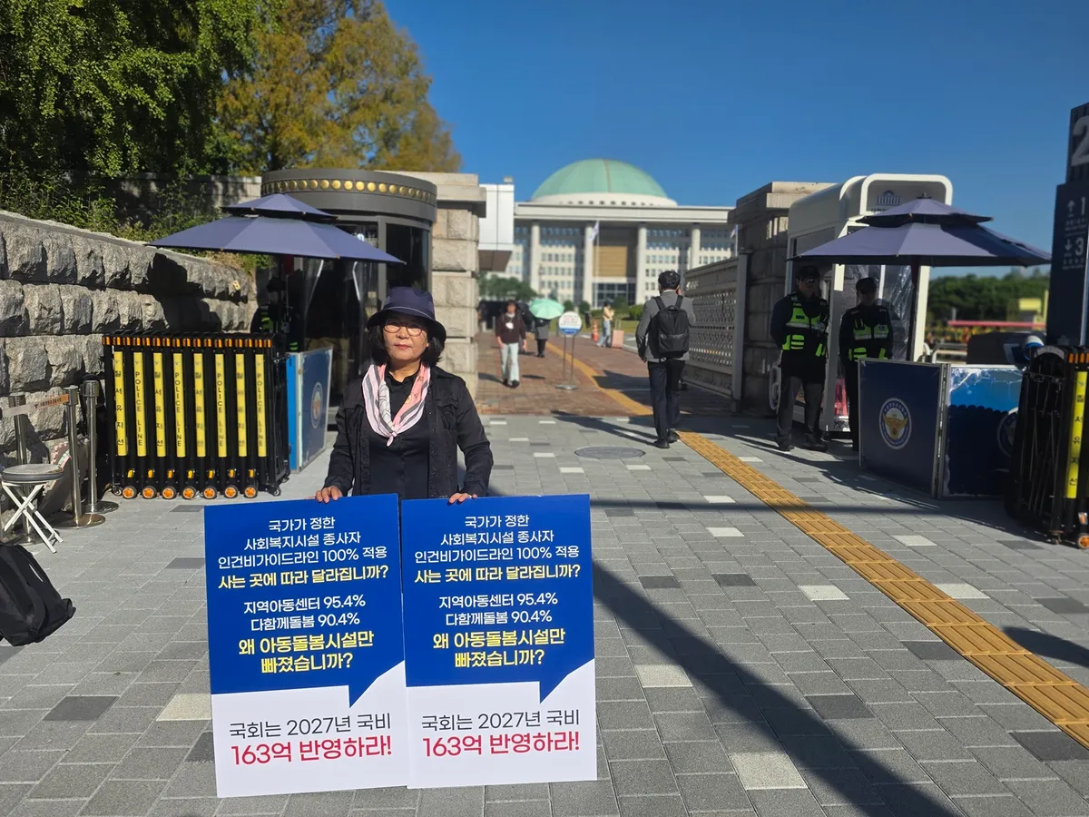 국정감사가 진행 중인 국회 정문 앞에서 한 지역아동센터 관계자가 인건비 가이드라인 100% 적용을 촉구하는 피켓을 들고 1인 시위를 벌이고 있다